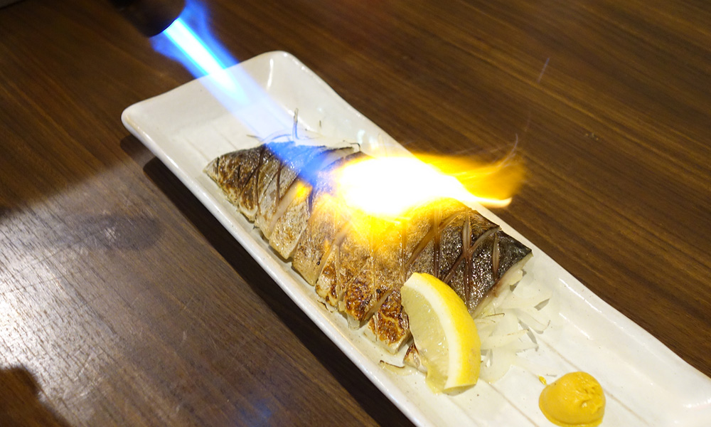 〆鯖を炙ってる写真